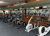 Thumbnail 10 of 26 - A gym with a variety of exercise equipment including treadmills, stationary bikes, and elliptical machines.