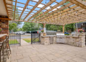 Thumbnail 15 of 27 - a patio with a pergola and an outdoor kitchen
