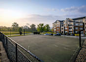 Thumbnail 23 of 29 - A basketball court is surrounded by a black fence and apartment buildings.