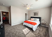 Thumbnail 15 of 29 - A spacious carpeted bedroom with a bed, a ceiling fan, and attached bathroom.