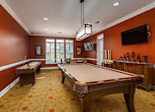 Thumbnail 19 of 29 - A pool table in a room with orange walls.