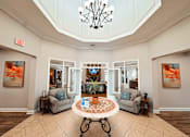 Thumbnail 18 of 29 - clubhouse area with a large, well-lit room with a chandelier, two couches, and a coffee table.