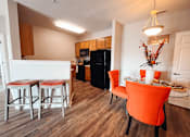 Thumbnail 12 of 29 - A kitchen with a black refrigerator and a dining table with chairs.