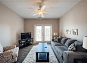 Thumbnail 2 of 29 - A living room with a grey couch, a coffee table, and a ceiling fan.