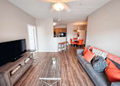 Thumbnail 14 of 29 - A living room with a grey couch and a wooden floor.