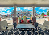 Thumbnail 20 of 29 - A patio with a table and chairs overlooking a pool and apartment building.