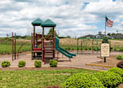 Thumbnail 27 of 29 - A playground with a green slide and a wooden structure with a red roof.