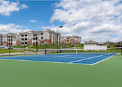 Thumbnail 24 of 29 - A tennis court in front of apartment buildings.