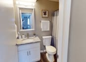 Thumbnail 7 of 20 - a bathroom with a toilet and a sink and a mirror