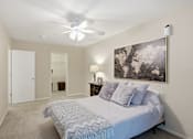 Thumbnail 7 of 35 - A bedroom with a bed, a ceiling fan, and a painting on the wall.