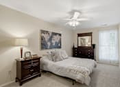 Thumbnail 6 of 35 - A bedroom with a bed, dresser, and ceiling fan.