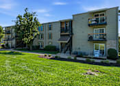Thumbnail 34 of 35 - Apartment complex with a grassy front yard and a clear blue sky.