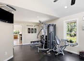 Thumbnail 16 of 35 - A community gym with a television, weights, and exercise equipment.