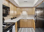 Thumbnail 4 of 35 - A kitchen with wooden cabinets and a black refrigerator.
