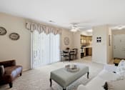 Thumbnail 2 of 35 - A living room with a brown leather couch, a white sofa, a coffee table, and a dining table with chairs.