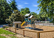 Thumbnail 24 of 35 - A playground with a yellow slide and a brown wooden fence.