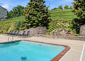 Thumbnail 17 of 35 - A pool with a waterfall and a stone wall.