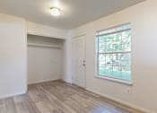 Thumbnail 12 of 35 - A room with a white door and a window with a view of trees.