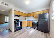 Thumbnail 2 of 35 - A kitchen with wooden cabinets and black appliances.