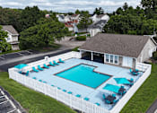 Thumbnail 22 of 35 - A pool surrounded by a white fence with blue umbrellas.