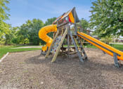 Thumbnail 9 of 12 - a swing set with a yellow slide in a park