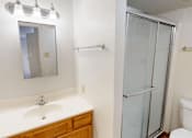 Thumbnail 16 of 27 - A bathroom with a sink, mirror, toilet and shower.