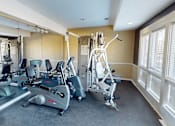 Thumbnail 25 of 27 - A gym with a treadmill, elliptical trainer and a weight machine.