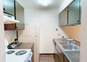 Thumbnail 3 of 27 - A small kitchen with a white stove and a white refrigerator.