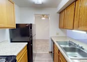 Thumbnail 7 of 27 - A kitchen with a black refrigerator and wooden cabinets.