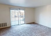 Thumbnail 9 of 27 - A room with a carpeted floor and a sliding glass door leading to a parking lot.