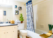 Thumbnail 11 of 26 - a bathroom with a white toilet next to a bath tub