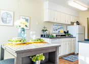 Thumbnail 6 of 26 - a kitchen with white cabinets and a wooden table with plates and glasses on it