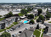 Thumbnail 31 of 33 - A view of a residential area with apartment buildings, a swimming pool, and cars parked in the parking lot.