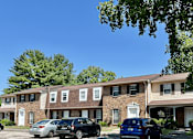 Thumbnail 1 of 8 - A row of townhouses with cars parked in front.