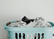 Thumbnail 6 of 8 - A light blue laundry basket filled with a pile of clothes.