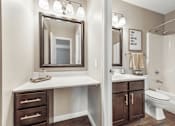 Thumbnail 14 of 35 - A bathroom with a white counter and brown drawers.