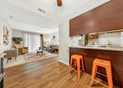 Thumbnail 7 of 35 - A living room with a bar area and orange stools.