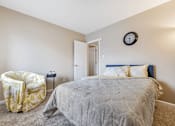 Thumbnail 11 of 35 - A bedroom with a bed, a chair, and a clock on the wall.