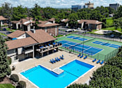 Thumbnail 30 of 35 - A tennis court surrounded by a pool and apartment buildings.
