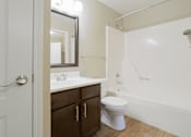 Thumbnail 16 of 35 - A white toilet sits in a bathroom with a white sink and a mirror.