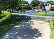 Thumbnail 31 of 35 - A tennis court is surrounded by a grassy area and trees.