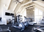 Thumbnail 13 of 17 - a gym with exercise machines and a stone fireplace