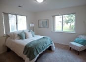 Thumbnail 2 of 34 - a bedroom with a bed and a chair and two windows