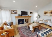 Thumbnail 14 of 19 - A living room with a fireplace and a television on the wall.