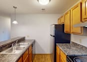 Thumbnail 2 of 19 - A kitchen with a black refrigerator and wooden cabinets.