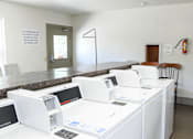 Thumbnail 17 of 19 - A laundromat with washing machines and a sign that says