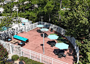 Thumbnail 20 of 26 - A patio with tables and chairs surrounded by a fence.