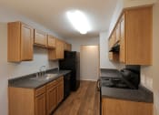Thumbnail 9 of 22 - an empty kitchen with wood cabinets and a black stove and refrigerator