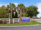 Thumbnail 21 of 22 - a sign in front of palm trees and a white fence