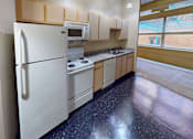 Thumbnail 7 of 30 - A kitchen with a white fridge, microwave, and stove top oven.